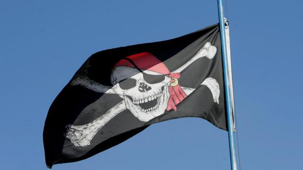 Eine Piratenflagge mit Totenkopf und gekreuzten Knochen weht im Wind.