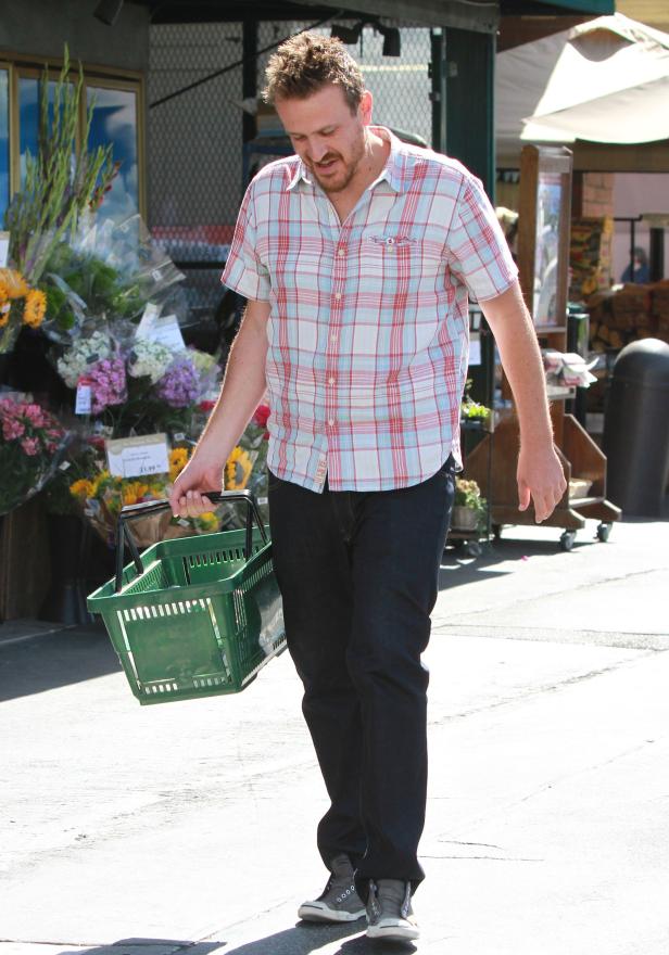 Jason Segel trägt einen grünen Einkaufskorb vor einem Blumenladen.