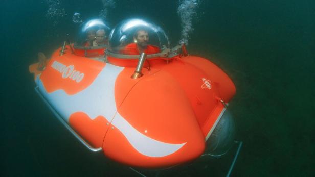Ein orangefarbenes U-Boot des Typs Nemo 100 mit zwei Personen unter Wasser.