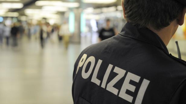 Ein Polizist steht in einer belebten Fußgängerzone.