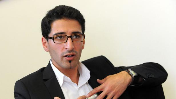 Ein Mann mit Brille und Anzug gestikuliert während eines Gesprächs.