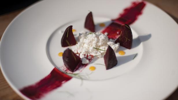 Ein Teller mit Rote Bete, Frischkäse und dekorativen Saucenklecksen.