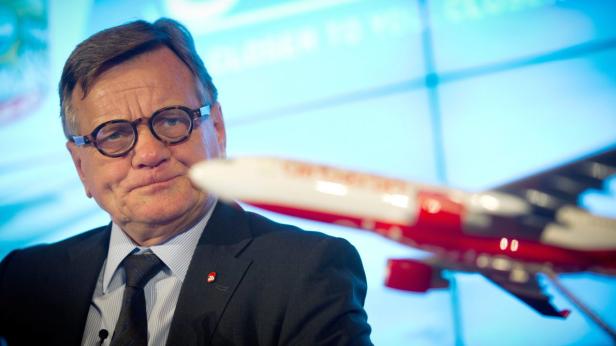 Ein Mann mit Brille steht vor einem Modellflugzeug.