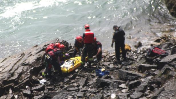 Rettungskräfte bergen eine verletzte Person am Ufer eines Flusses.