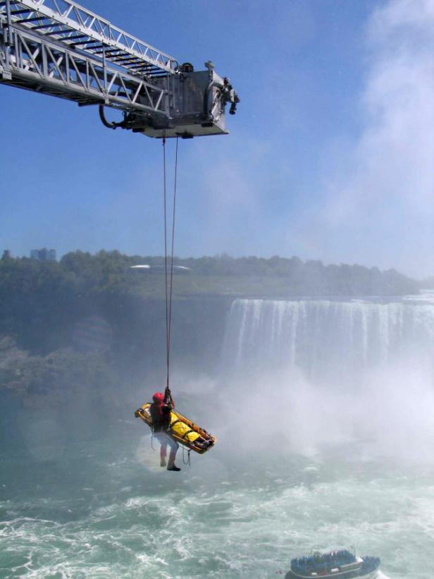 Ein Mann wird mit einer Trage von einem Kran über den Niagarafällen abgeseilt.