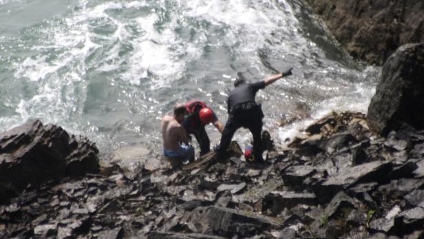 Ein Mann wird von einem Polizisten und einem Rettungsschwimmer aus dem Wasser gezogen.