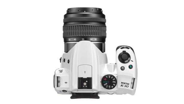 Eine weiße Pentax K-30 DSLR-Kamera von oben mit aufgesetztem Objektiv.
