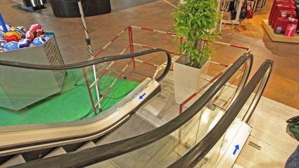 Eine Rolltreppe in einem Einkaufszentrum, dekoriert mit Fußbällen und einer Pflanze.