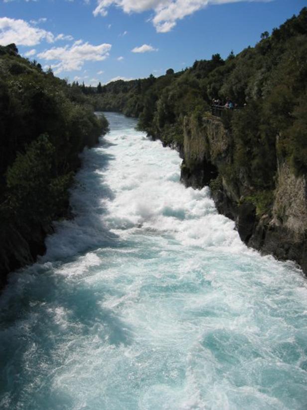 Türkisfarbenes Wasser stürzt sich durch eine enge Schlucht mit üppiger Vegetation.