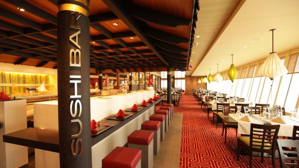 Innenansicht eines Sushi-Restaurants mit Bar und Tischen.