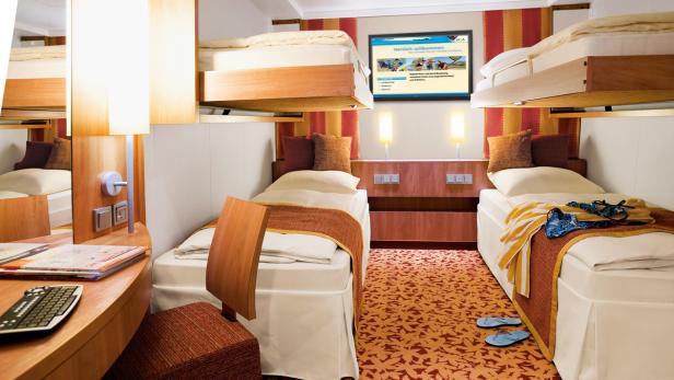 Eine Kabine mit zwei Einzelbetten und zwei Hochbetten auf einem Kreuzfahrtschiff.