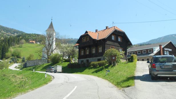 Eine malerische Landschaft mit einer Kirche, einem traditionellen Haus und einem Gasthof.