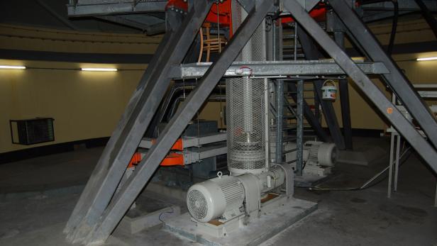 Eine Industrieanlage mit Motoren, Metallstrukturen und einem Stuhl im Hintergrund.