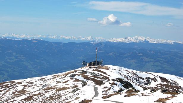 Auf einem schneebedeckten Berg steht ein Gebäude mit einem hohen Sendemast.