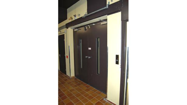 Ein Aufzug mit braunen Türen und einem Bedienfeld mit Knöpfen.