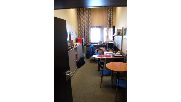 Ein Büro mit Schreibtischen, Stühlen und einem kleinen runden Tisch.