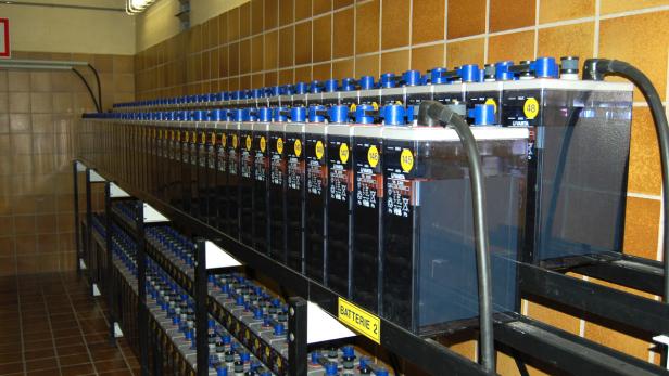 Ein Raum mit mehreren Reihen von Varta-Batterien auf Metallregalen.