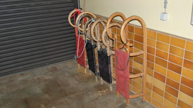 Mehrere Holzschlitten stehen an einer Wand.