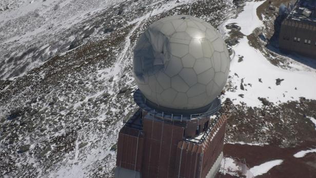 Eine Radarkuppel auf einem Berg mit Schnee bedeckt.