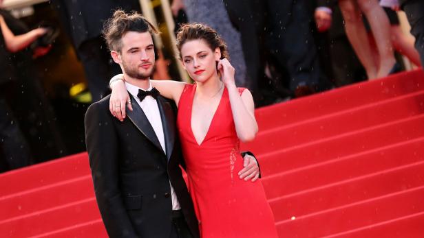 Kristen Stewart in einem roten Kleid mit einem Mann auf einem roten Teppich.