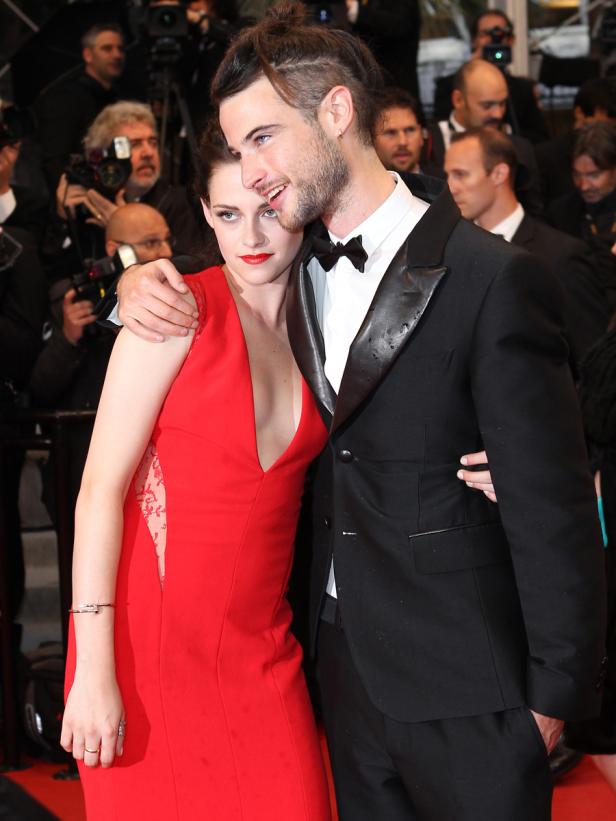 Kristen Stewart und ein Mann im Anzug posieren auf einem roten Teppich.