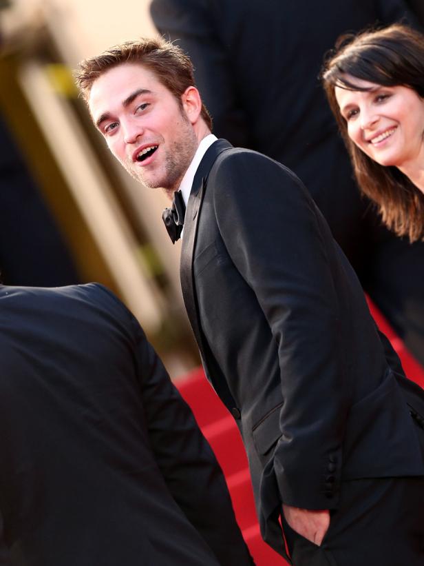 Robert Pattinson auf einem roten Teppich, gekleidet in einem schwarzen Anzug.