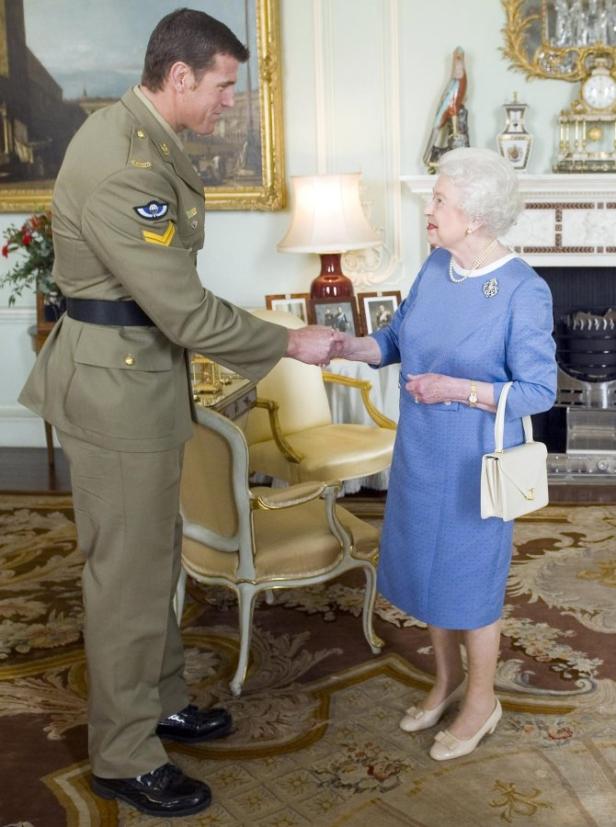 Königin Elisabeth II. schüttelt einem Mann in Militäruniform die Hand.