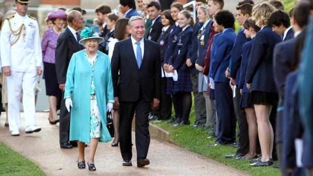 Königin Elisabeth II. geht mit einem Mann an einer Reihe von Schulkindern vorbei.