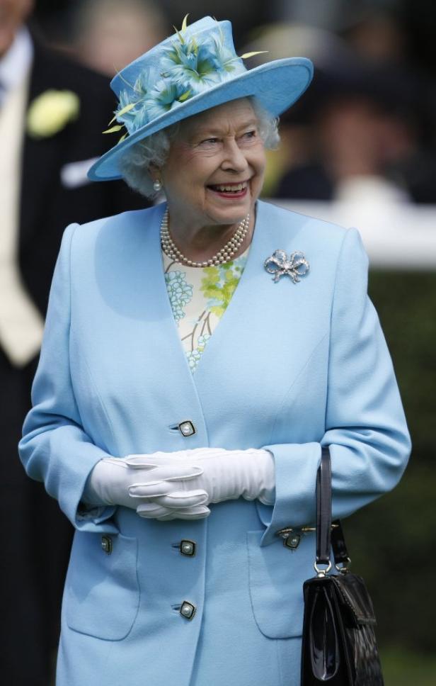 Königin Elisabeth II. lächelt in einem hellblauen Hut und Mantel.