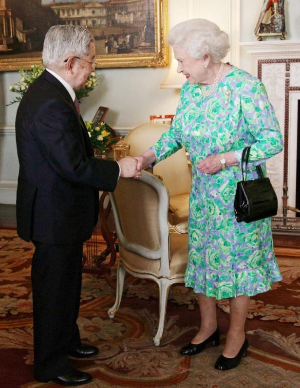 Königin Elisabeth II. schüttelt einem Mann die Hand.