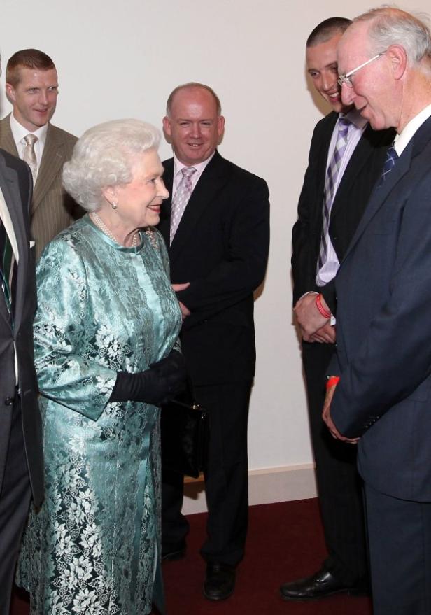 Königin Elisabeth II. in einem Gespräch mit mehreren Männern.