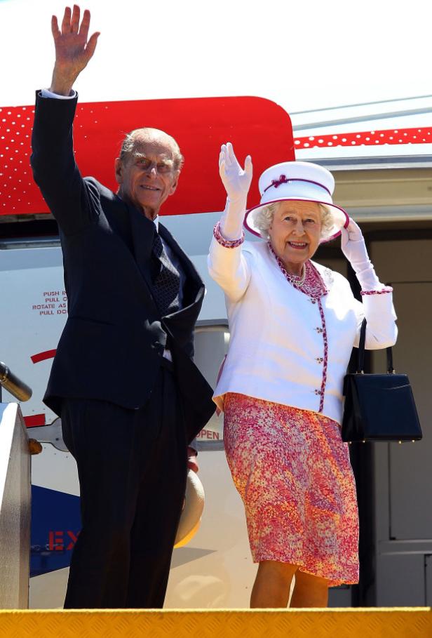 Königin Elisabeth II. und Prinz Philip winken von einer Flugzeugtreppe.