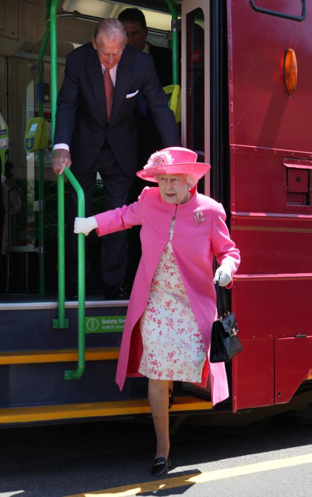 Königin Elisabeth II. steigt aus einer roten Straßenbahn.