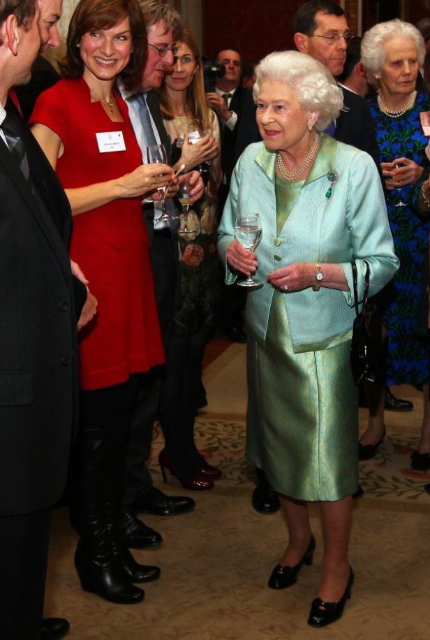 Königin Elisabeth II. hält ein Glas Wasser bei einer Veranstaltung mit anderen Gästen.