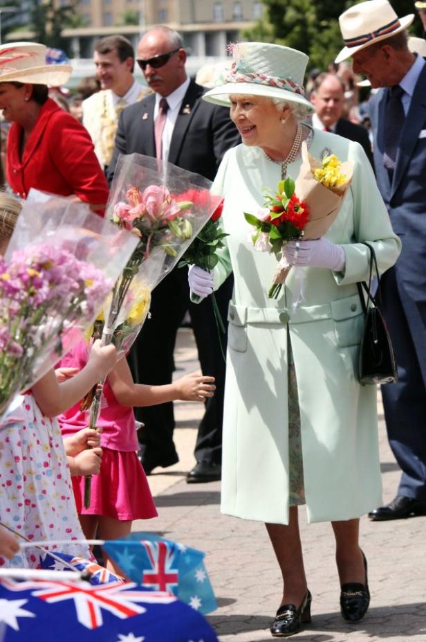 Königin Elisabeth II. nimmt Blumen von Kindern entgegen.
