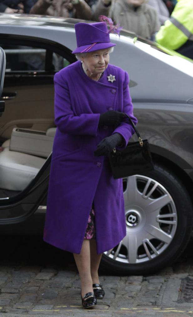 Königin Elisabeth II. steigt aus einem Auto in einem lila Mantel und Hut.
