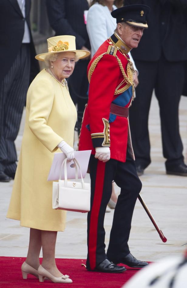 Königin Elisabeth II. und Prinz Philip schreiten über einen roten Teppich.