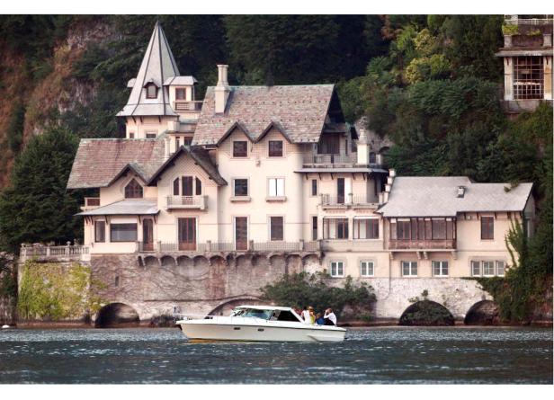 Ein Ausflugsboot fährt an einem großen Haus am Wasser entlang.