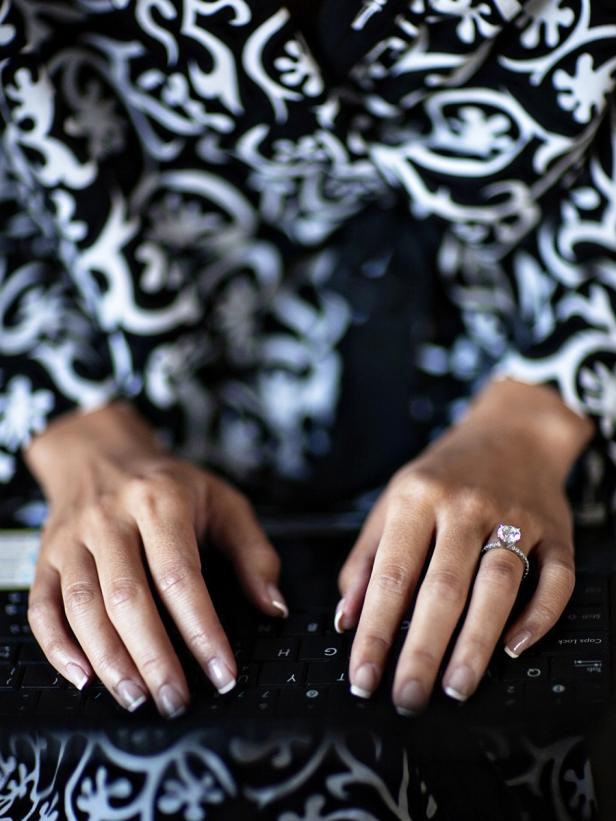 Eine Frau tippt auf einer Laptop-Tastatur und trägt einen auffälligen Ring.
