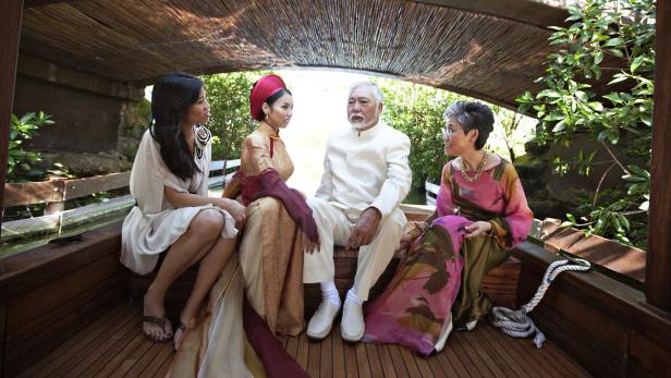 Eine Familie sitzt in einem Boot unter einem schattigen Dach.