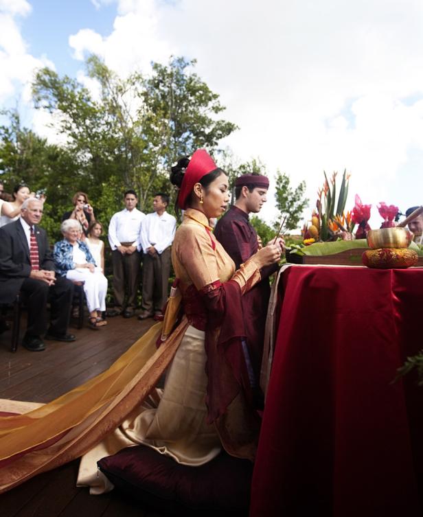 Ein Paar in traditioneller vietnamesischer Kleidung kniet während einer Zeremonie.