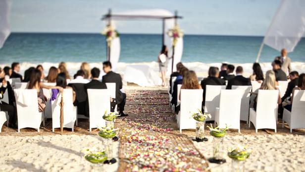 Eine Hochzeitszeremonie findet am Strand vor dem Meer statt.