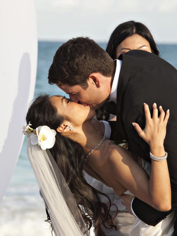 Ein Brautpaar küsst sich vor dem Hintergrund des Meeres.