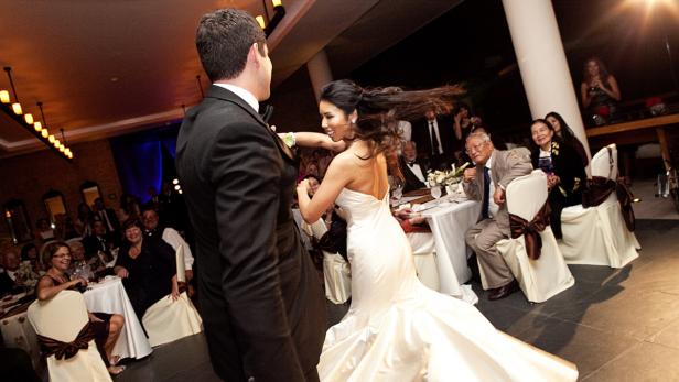 Eine Braut tanzt mit dem Bräutigam auf ihrer Hochzeit, während die Gäste zusehen.