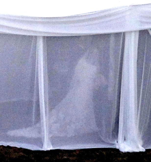 Eine Braut in einem weißen Kleid steht hinter einem Schleier.