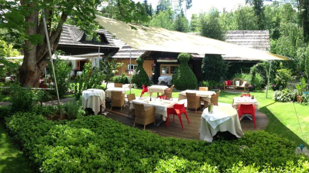 Einladender Außenbereich eines Restaurants mit Tischen und Sonnenschutz.