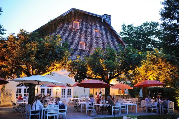Ein Restaurant mit Tischen und Sonnenschirmen im Freien vor einem großen Gebäude.