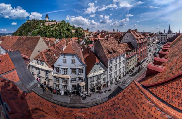 Blick über die Dächer von Graz mit dem Schlossberg im Hintergrund.