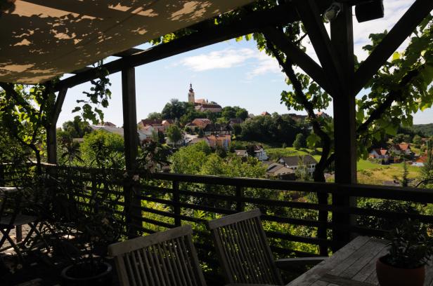 Blick von einer Terrasse auf eine Ortschaft mit Kirche auf einem Hügel.