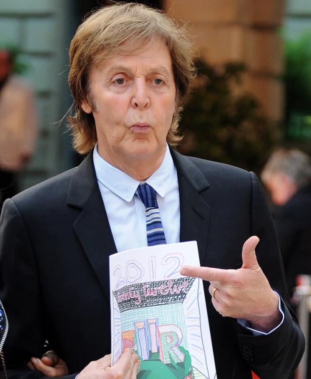 Paul McCartney zeigt auf ein Programmheft mit der Aufschrift „2012 Triniy Laban“.
